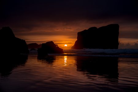 el sol se pone detrás de las rocas de la playa